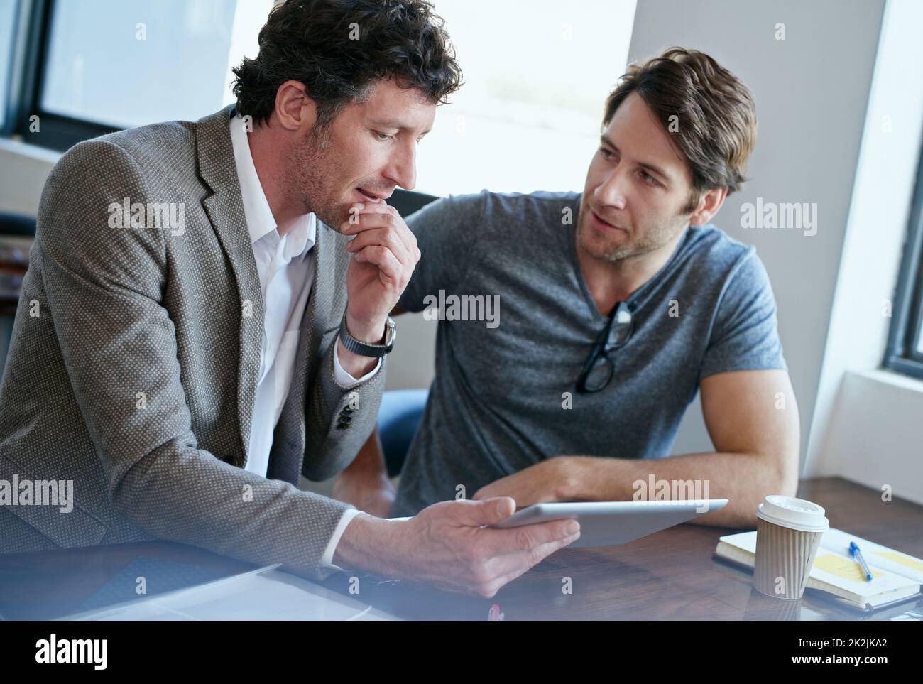 Working wirelessly. two handsome businessmen working on a digital tablet. Stock Photo