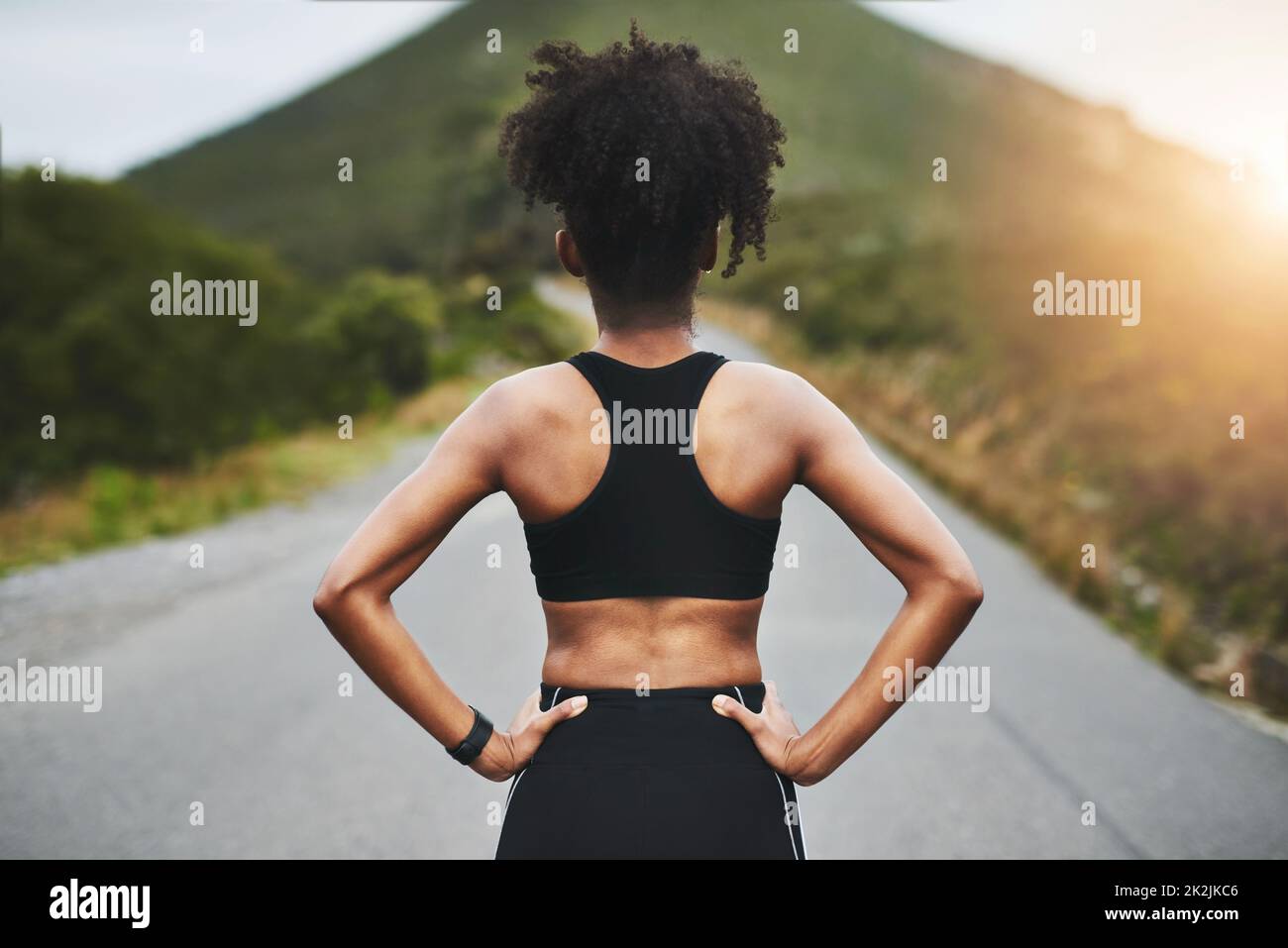 Time to get back on track. Rearview shot of an unrecognizable young sportswoman standing with her hands on her hips outside. Stock Photo