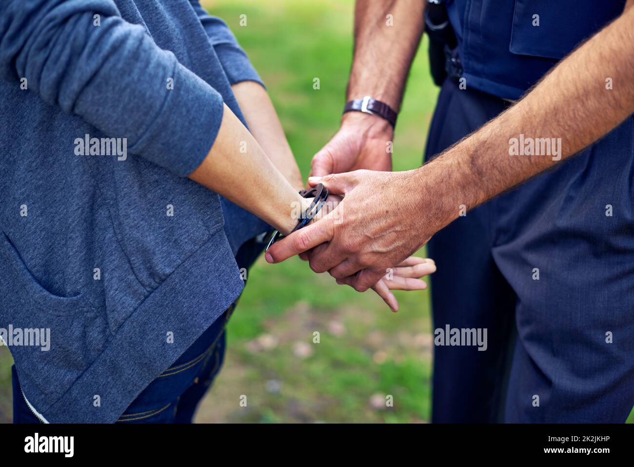 Thatll hold you. Cropped shot of a policemans hands putting cuffs on a suspect. Stock Photo