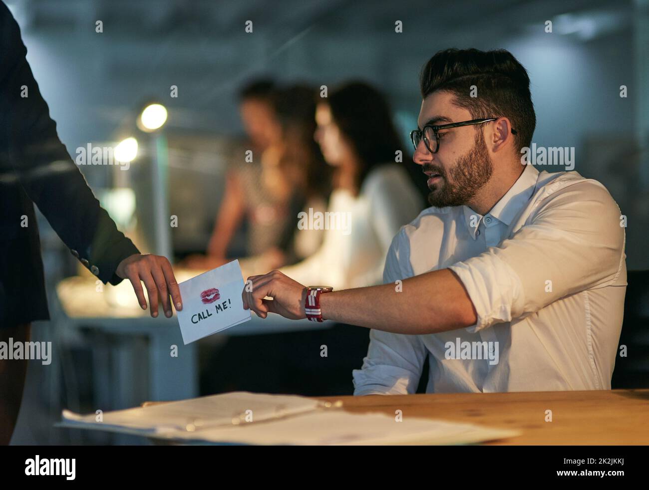 Office romance. Cropped shot of a love note being passed from one colleague to another. Stock Photo