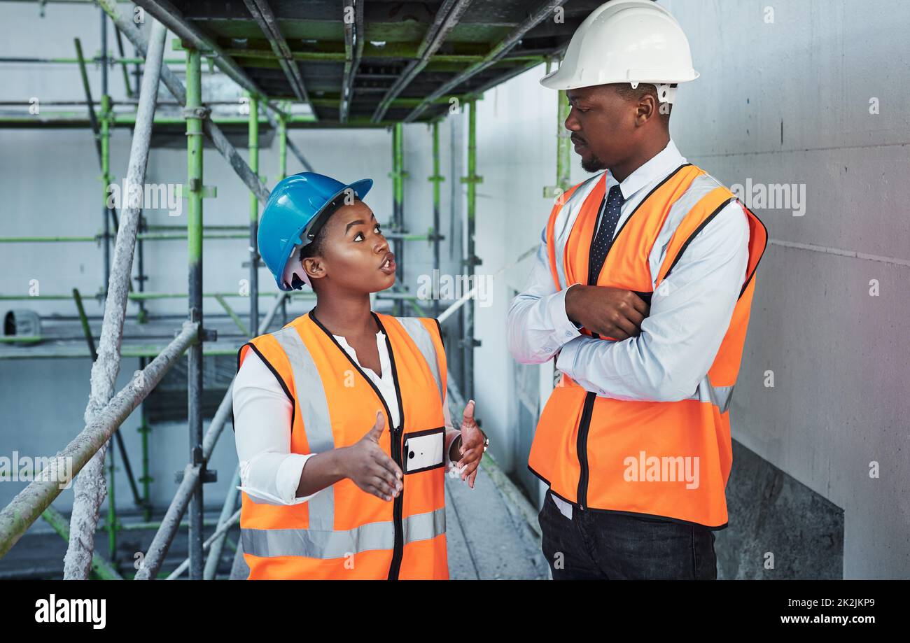 Combined skills are the building blocks of success. Shot of a young man and woman having a discussion while working at a construction site. Stock Photo