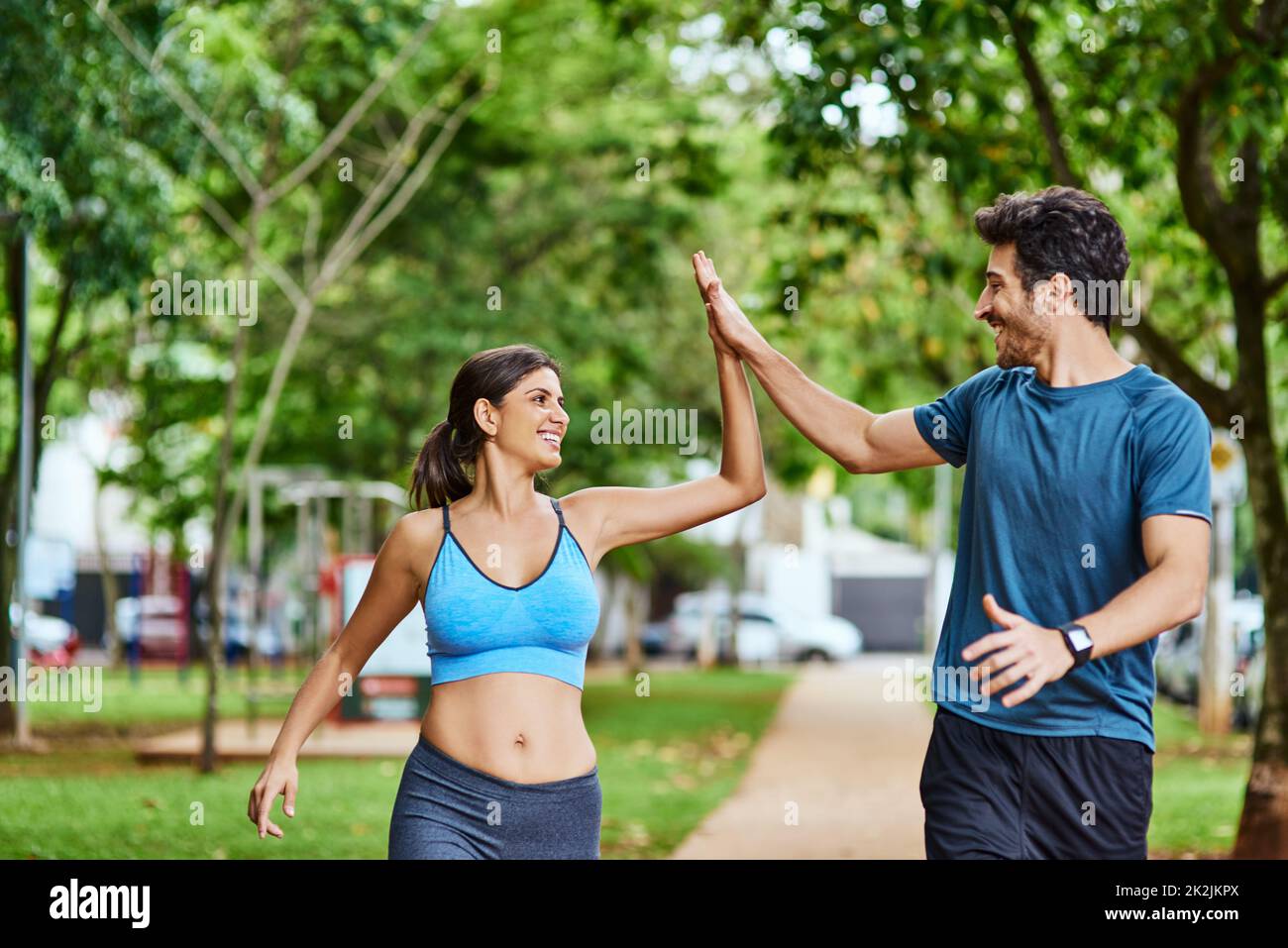 Thats just what we needed to get our hearts racing. Shot of a sporty young couple high fiving while exercising outdoors. Stock Photo