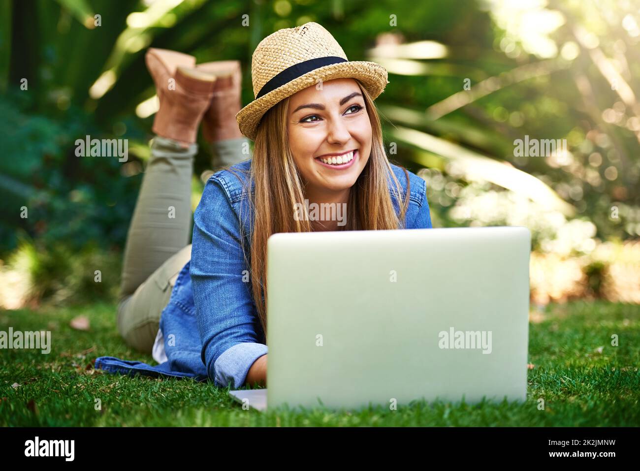 Thinking about her next article. Shot of an attractive young woman using her laptop while outside on the grass. Stock Photo