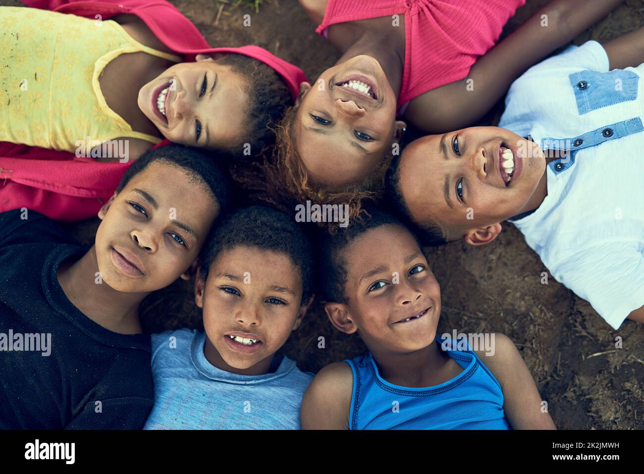 Kids will be kids. High angle portrait of children lying on the grass together outside. Stock Photo