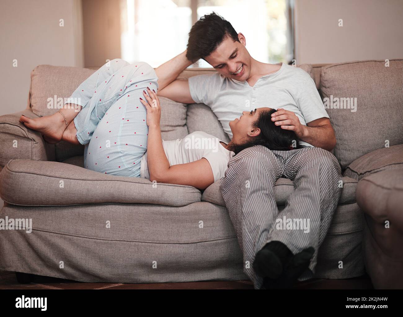 I could stare at you all day. Full length shot of an attractive young woman lying on her boyfriends lap on the living room sofa. Stock Photo