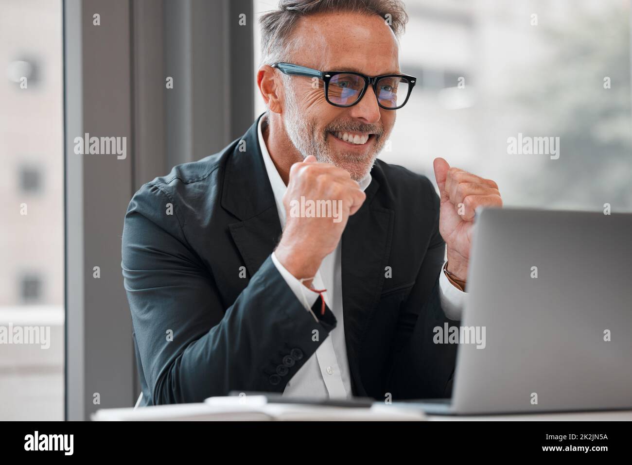 Success comes naturally. Cropped shot of a handsome mature businessman cheering while working on his laptop at a desk in the office. Stock Photo