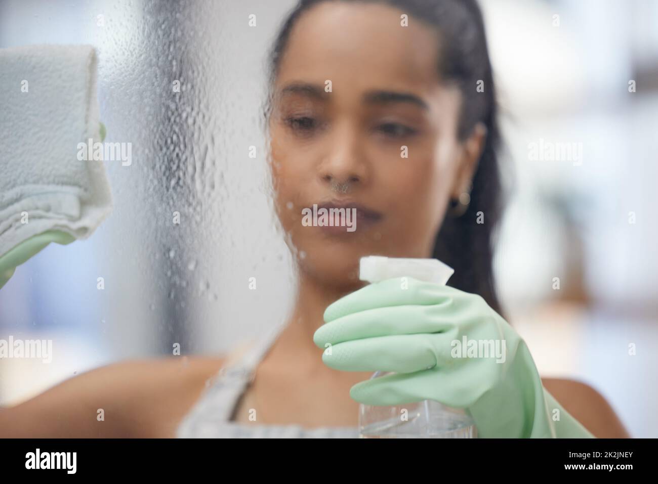 Shot of a young woman cleaning windows at home Stock Photo Alamy