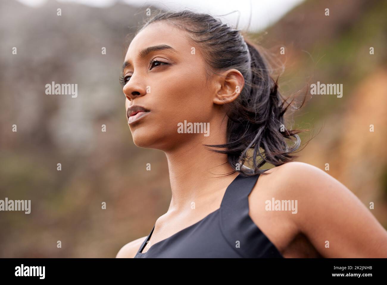 You can do it out your MIND into it. Shot of a fit young woman catching her breathe while completing her jog outdoors. Stock Photo