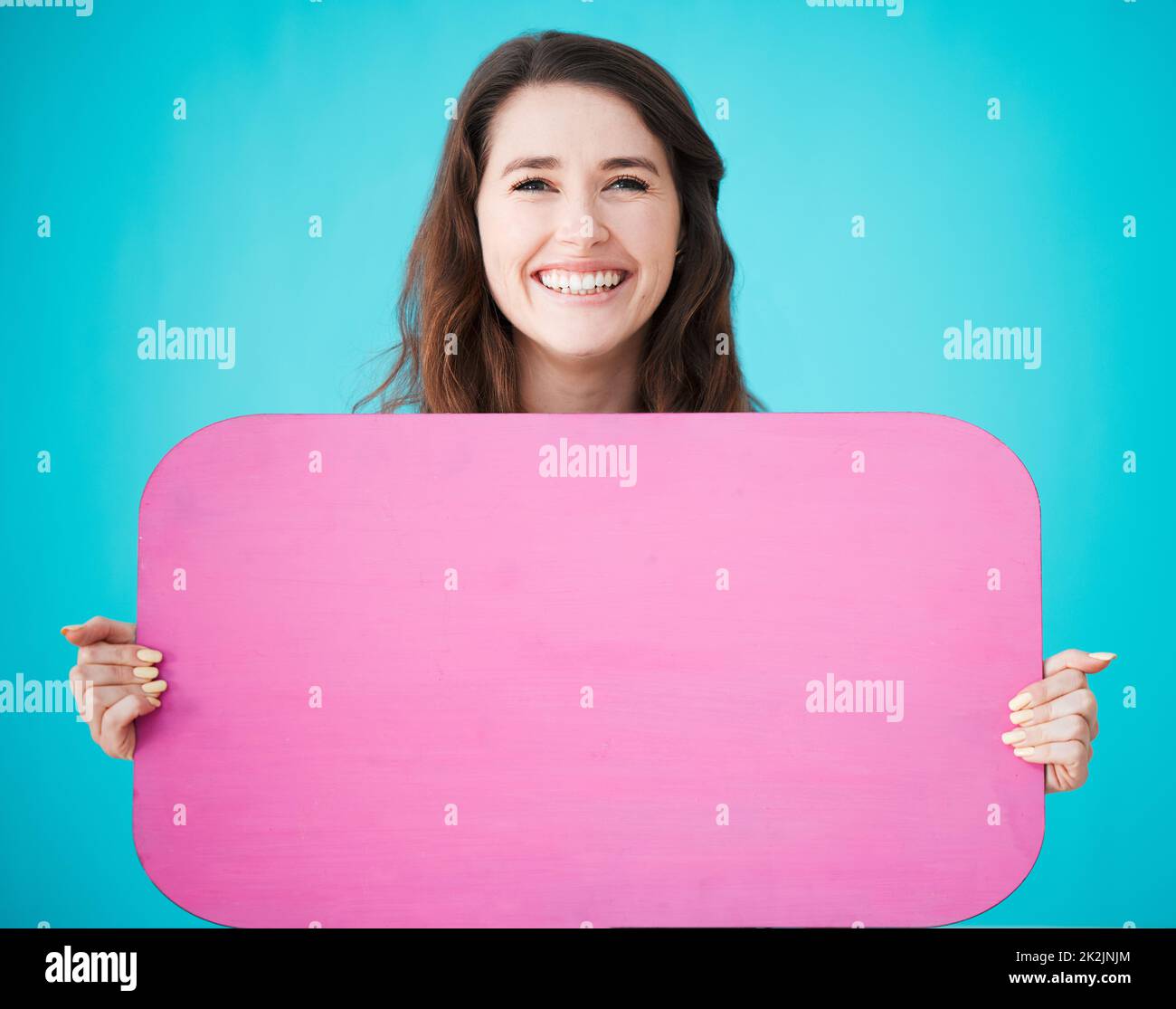 Picture your name, here. Studio portrait of an attractive young woman holding up a blank sign against a blue background. Stock Photo