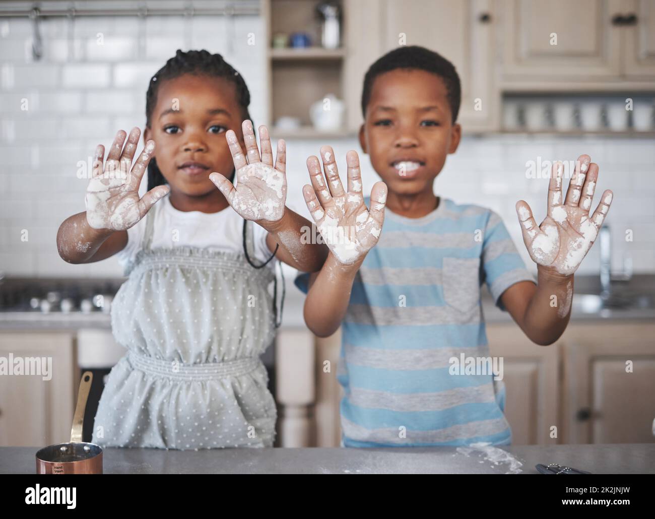 Dirty hands, pure hearts. Shot of a little girl and boy having fun while baking together at home. Stock Photo