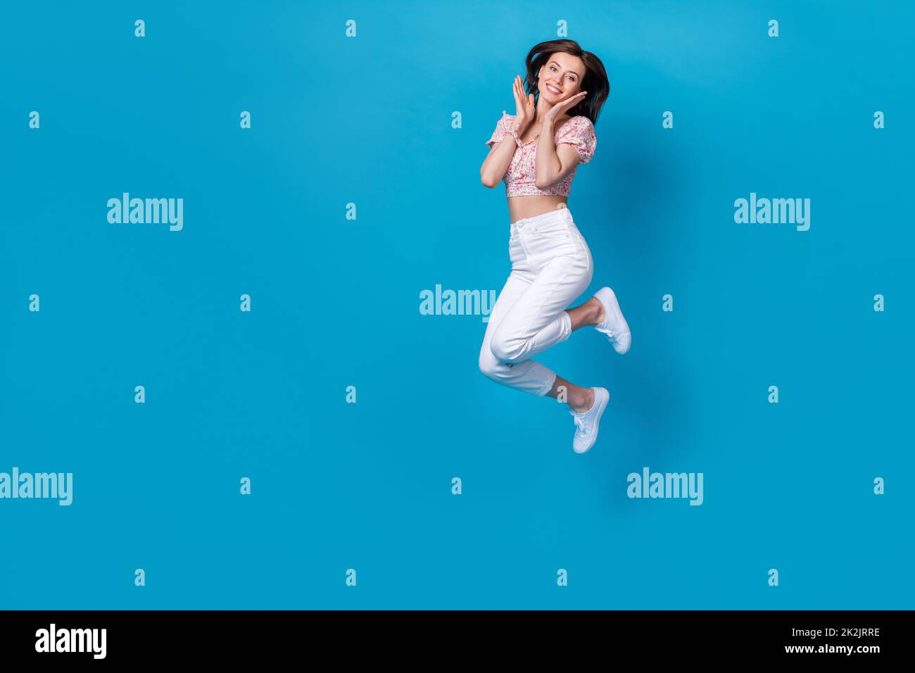 Photo of cute adorable inspired pretty lady jump arm cheekbones wear stylish outfit empty space isolated on blue color background Stock Photo