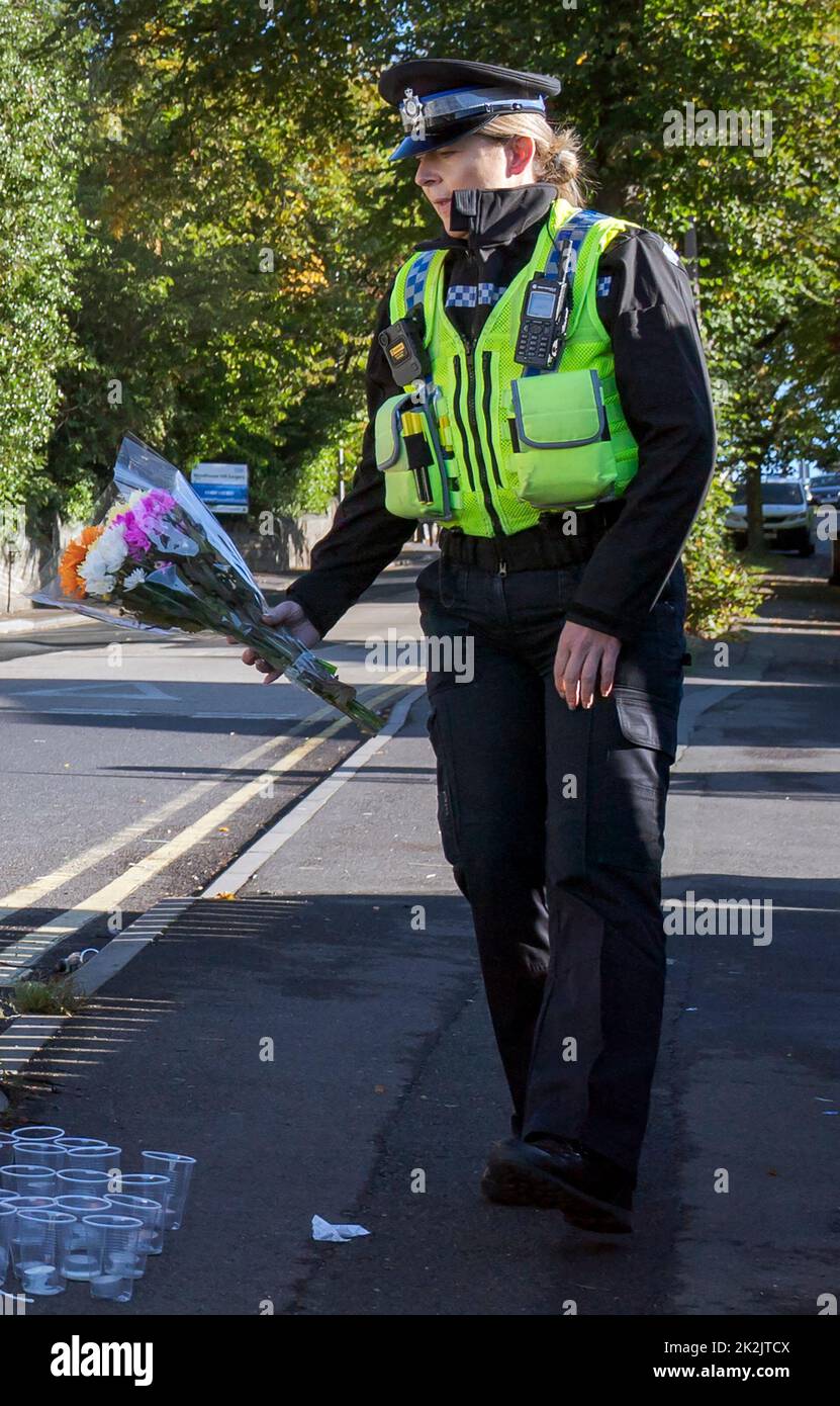 A police community support officer lays a floral tribute at the scene in Woodhouse Hill, Huddersfield, where 15-year-old schoolboy Khayri McLean was fatally stabbed outside his school gates. Picture date: Friday September 23, 2022. Stock Photo