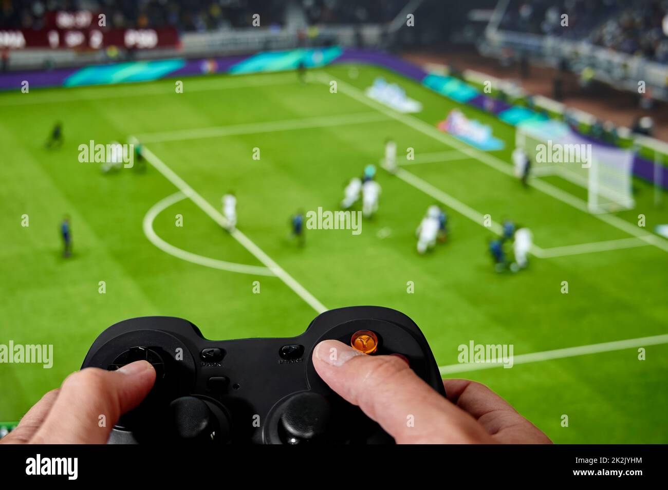Man operating a game controller in front of a screen to play a soccer