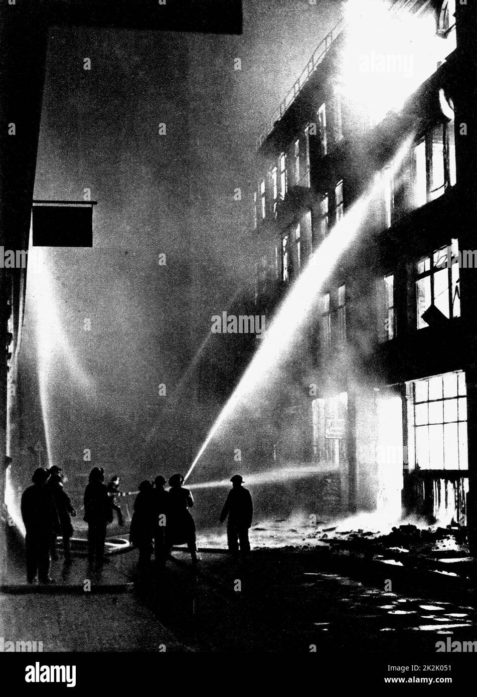 World War II 1939-1945. Firemen fighting a blazing City warehouse after a German air raid during the London Blitz, 1940. Stock Photo