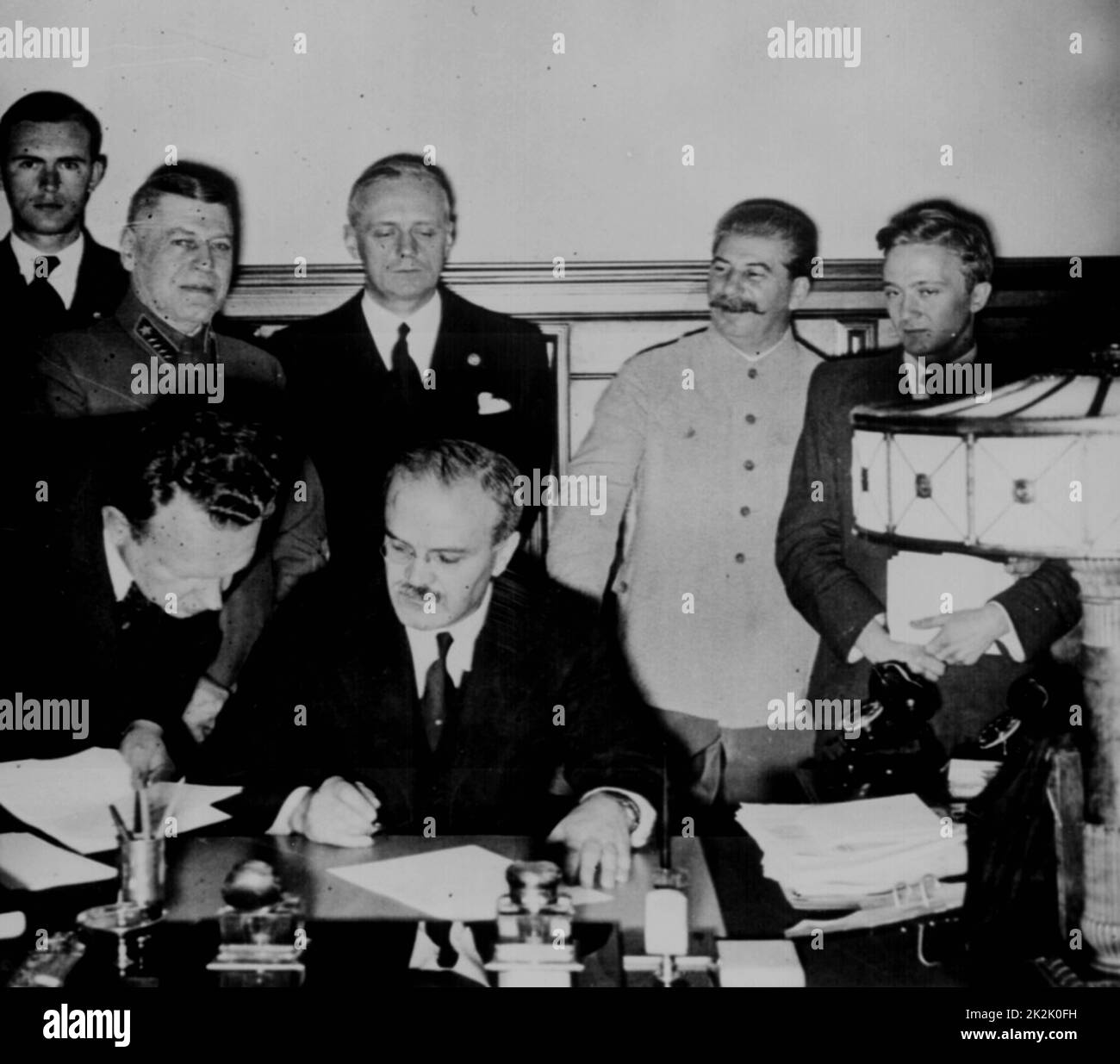 Soviet Foreign Commissar Vyacheslav Molotov signs the German-Soviet nonaggression pact; Joachim von Ribbentrop and Josef Stalin stand behind him. Moscow, August 23. 1939.World War II Stock Photo