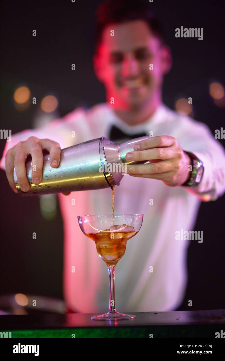 Bespoke cocktails just for you. Shot of a bartender pouring a drink into a glass in a nightclub. Stock Photo