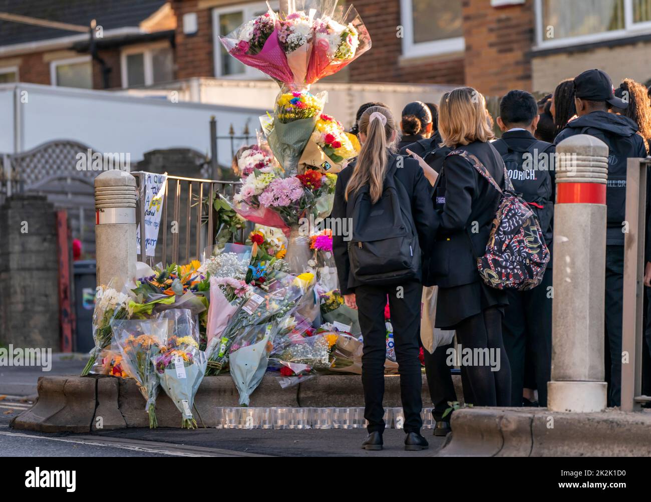 Pupils look at floral tributes at the scene in Woodhouse Hill, Huddersfield, where 15-year-old schoolboy Khayri McLean was fatally stabbed outside his school gates. Picture date: Friday September 23, 2022. Stock Photo