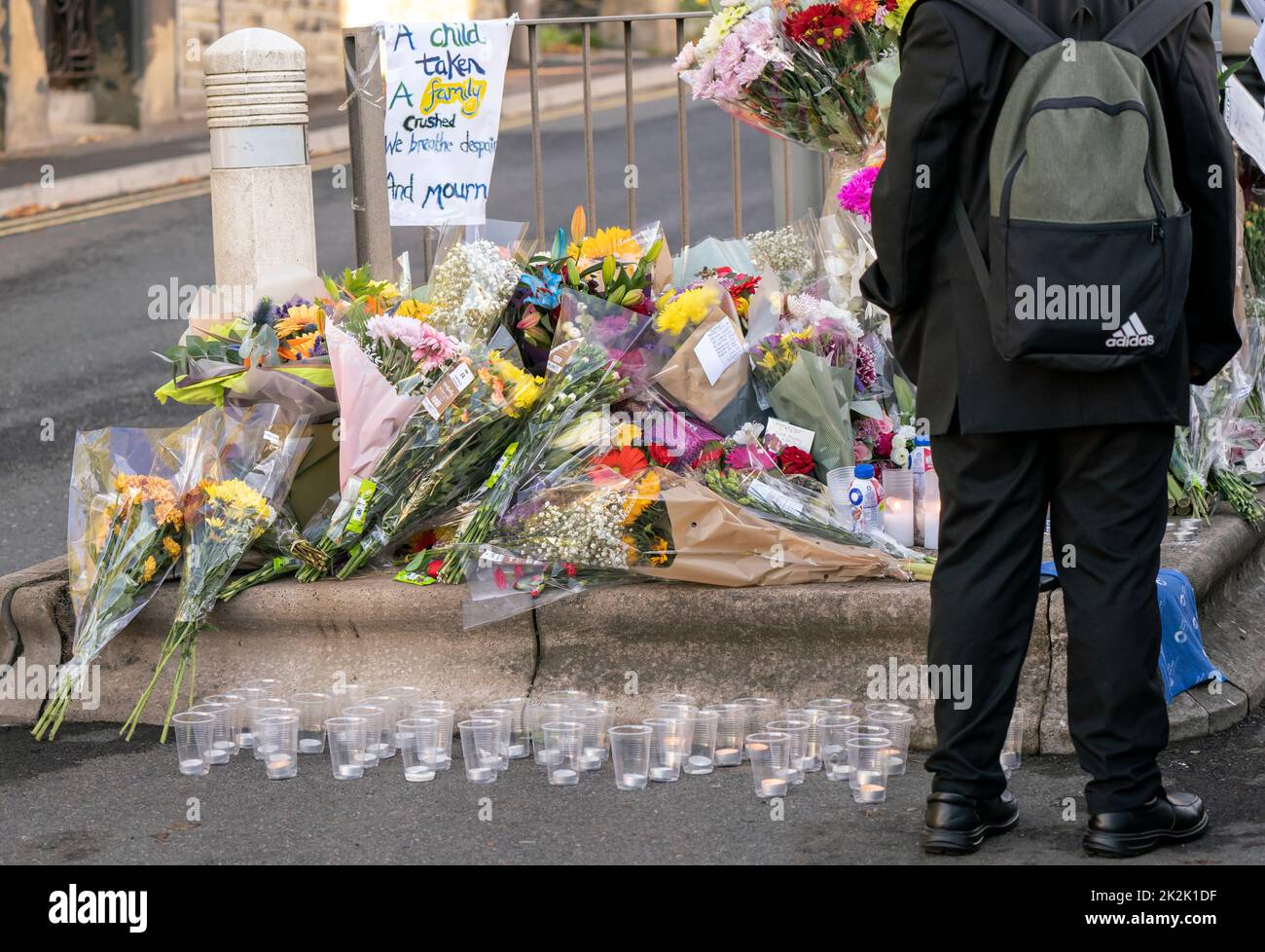 A pupil looks at floral tributes at the scene in Woodhouse Hill, Huddersfield, where 15-year-old schoolboy Khayri McLean was fatally stabbed outside his school gates. Picture date: Friday September 23, 2022. Stock Photo