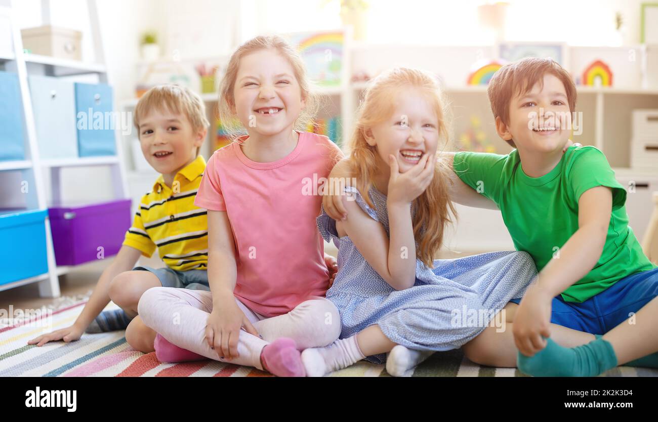 Group of children sitting indoors on the floor and looking in the camera. Stock Photo