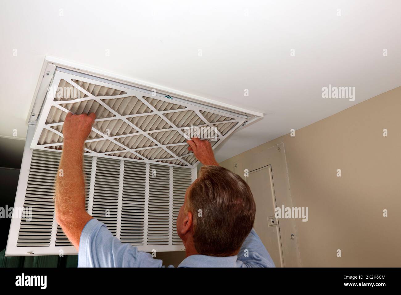 Adult Male Removing Air Filter from a Home Furnace Ceiling Vent Stock