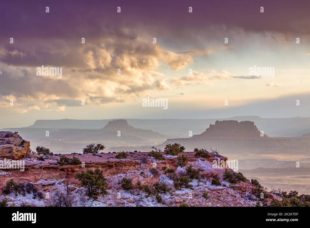 Storm clouds over Elaterate Butte, left, and Ekker Butte, right, from Candlestick Tower Overlook, Canyonlands NP, Utah.  Orange Cliffs behind in the G Stock Photo