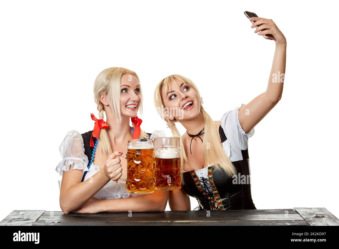Young women in traditional Bavarian clothes, dirndl or tracht, on white background. Stock Photo
