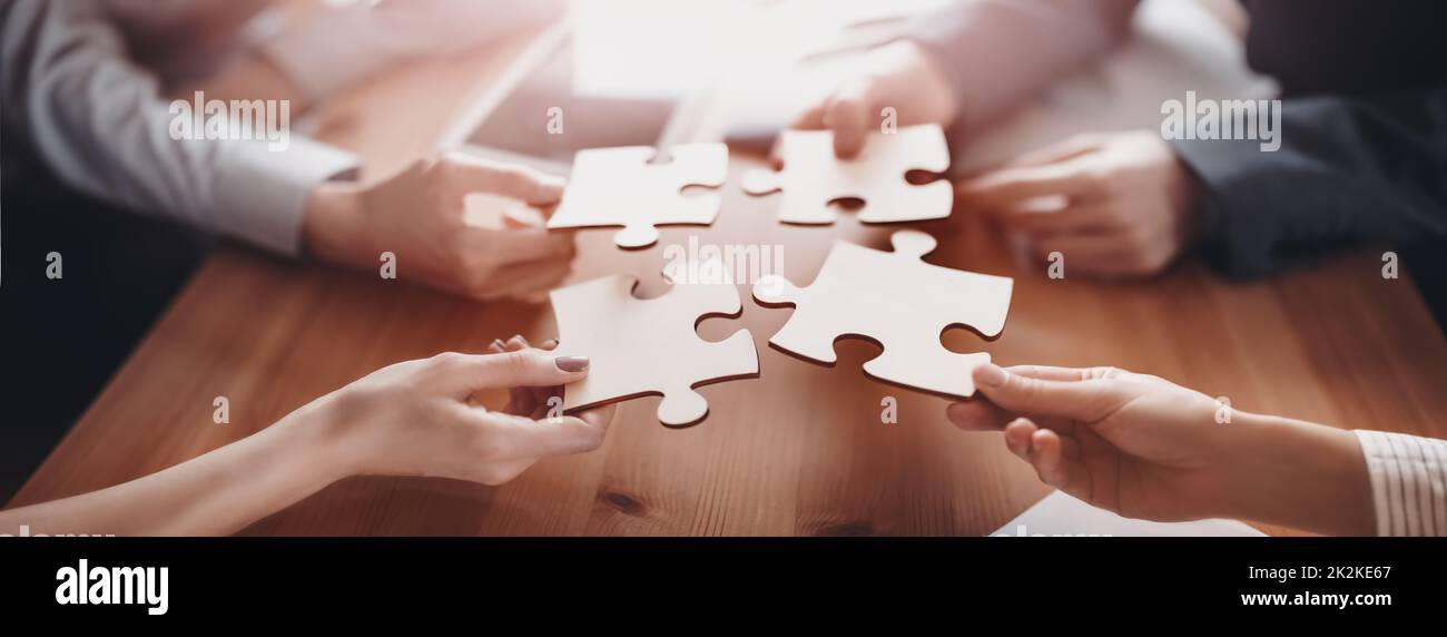 Buisnesswomen and buisnessmen working together while putting together puzzles. Stock Photo