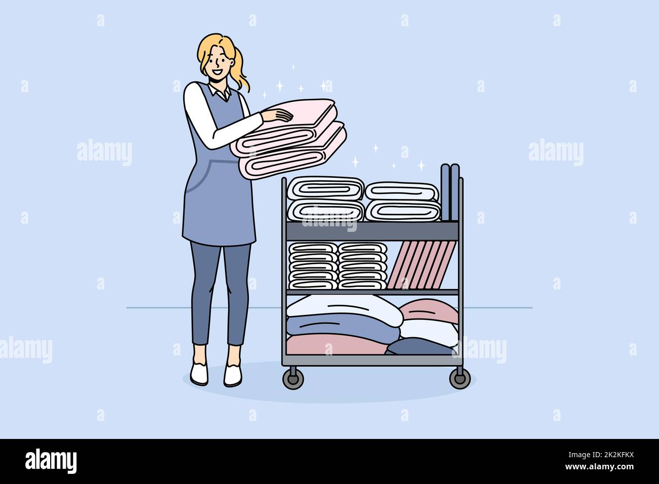 Smiling housekeeper with trolley with clean towels Stock Photo