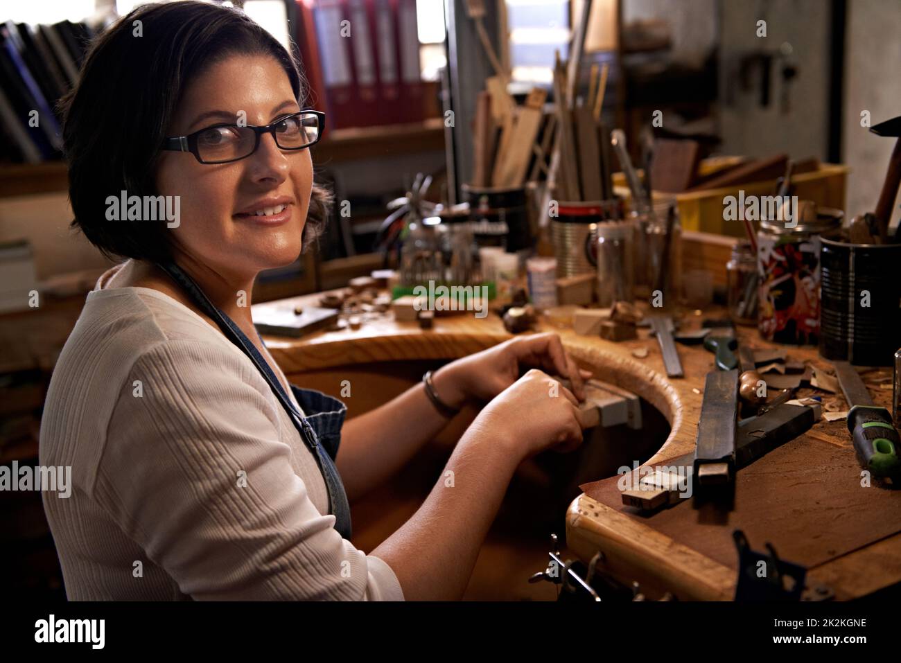 Creativity at work. A happy young woman working at a woodworking bench. Stock Photo