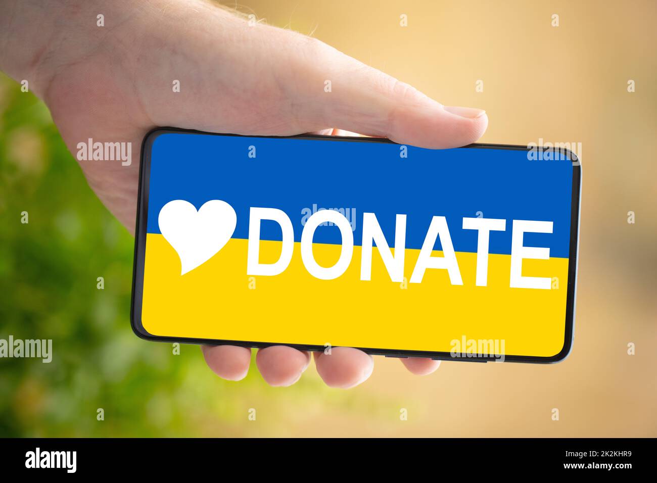 Male hand hold a cellphone - conceptual for donate and support for Ukraine. Stock Photo