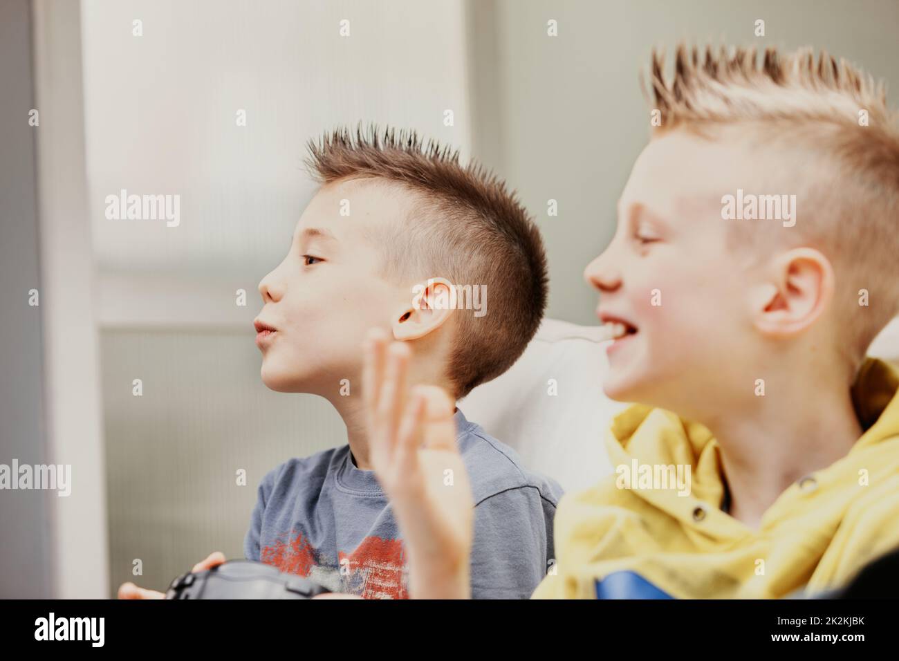 Two laughing young boys at home looking to side Stock Photo