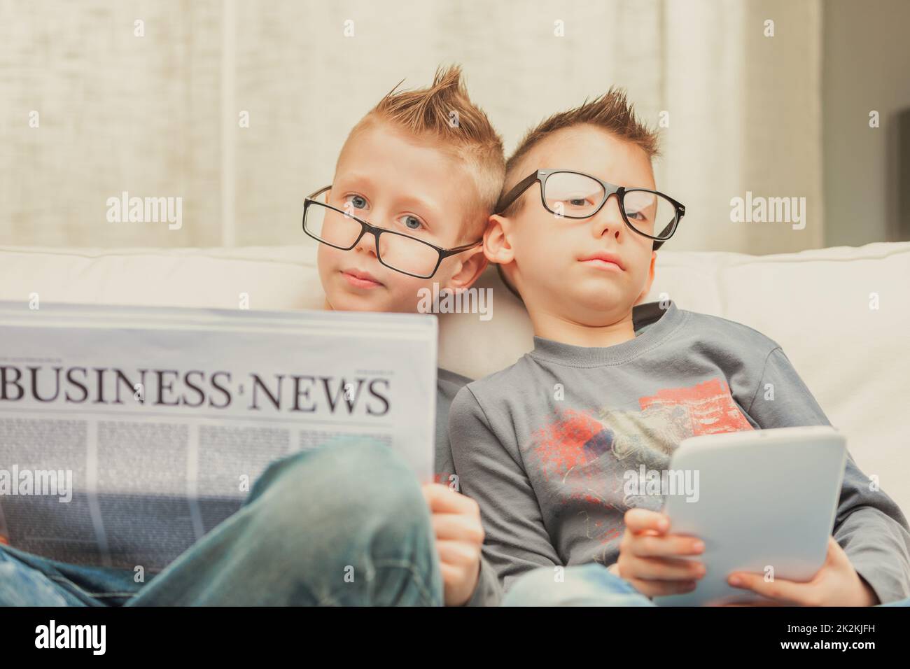 Two young brothers wearing glasses relaxing on a sofa Stock Photo Alamy