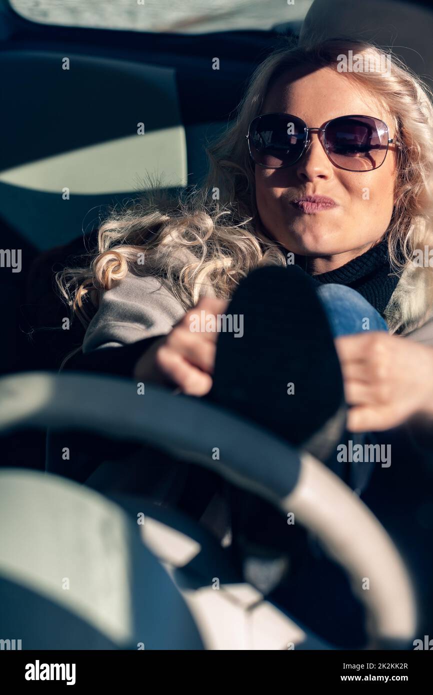 Impatient young woman tying laces while driving Stock Photo