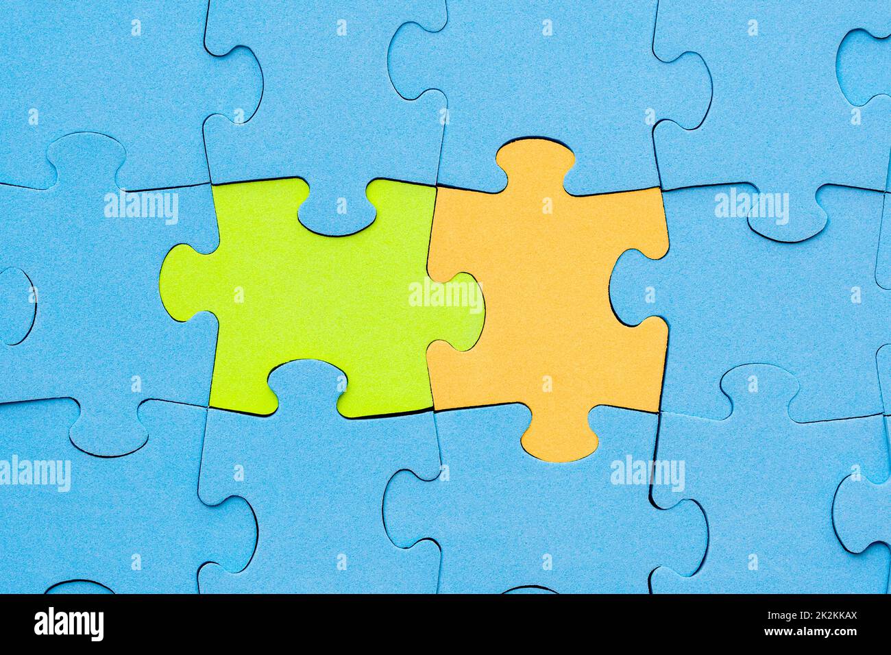 Green and yellow jigsaw puzzle pieces stands out from the crowd Stock Photo