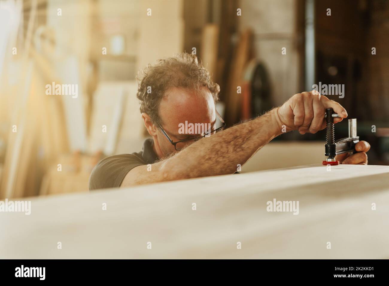 Carpenter adjusting a clamp on a plank of wood Stock Photo Alamy