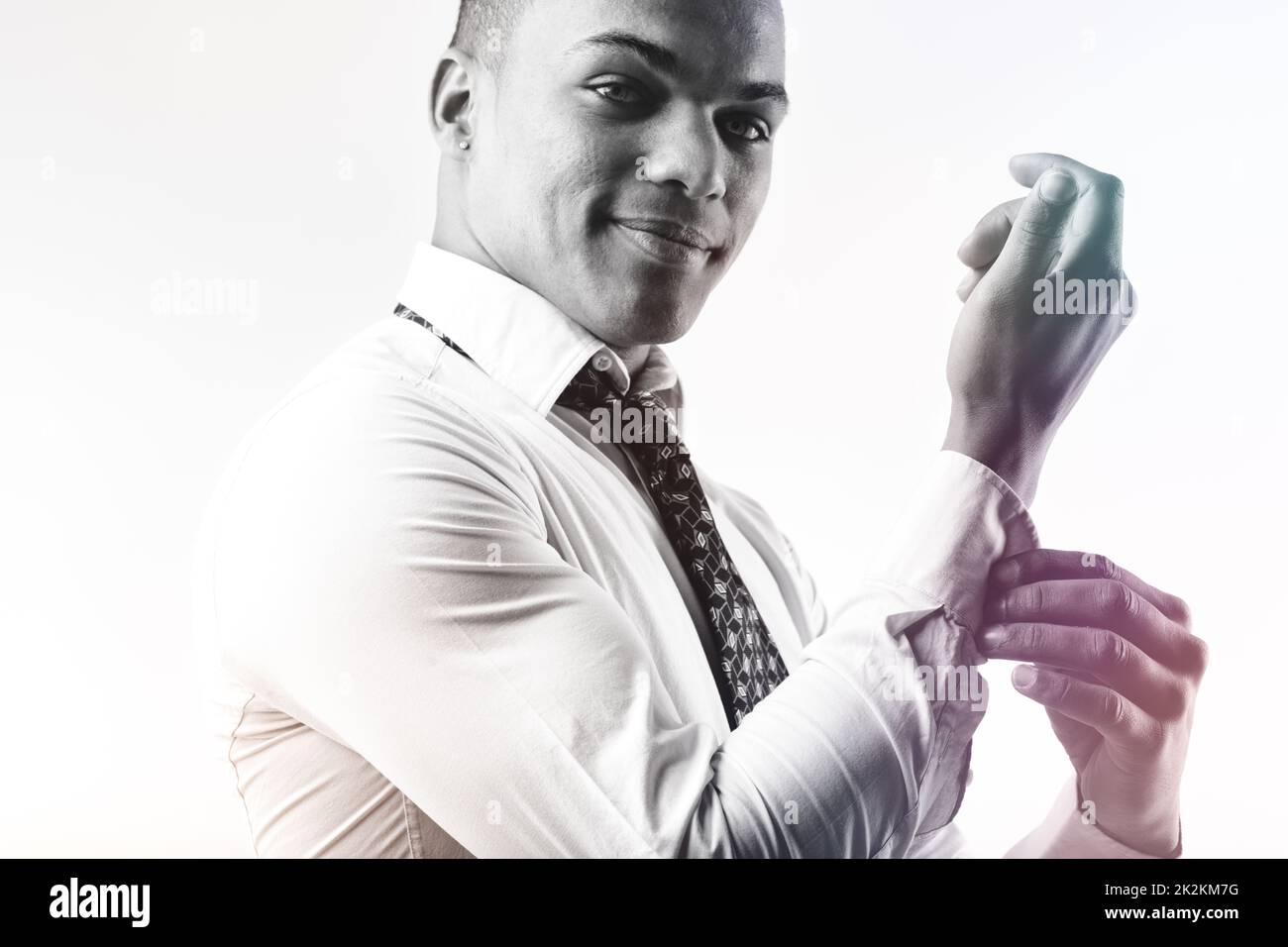 Handsome young Black man fastening the cuffs of his shirt Stock Photo