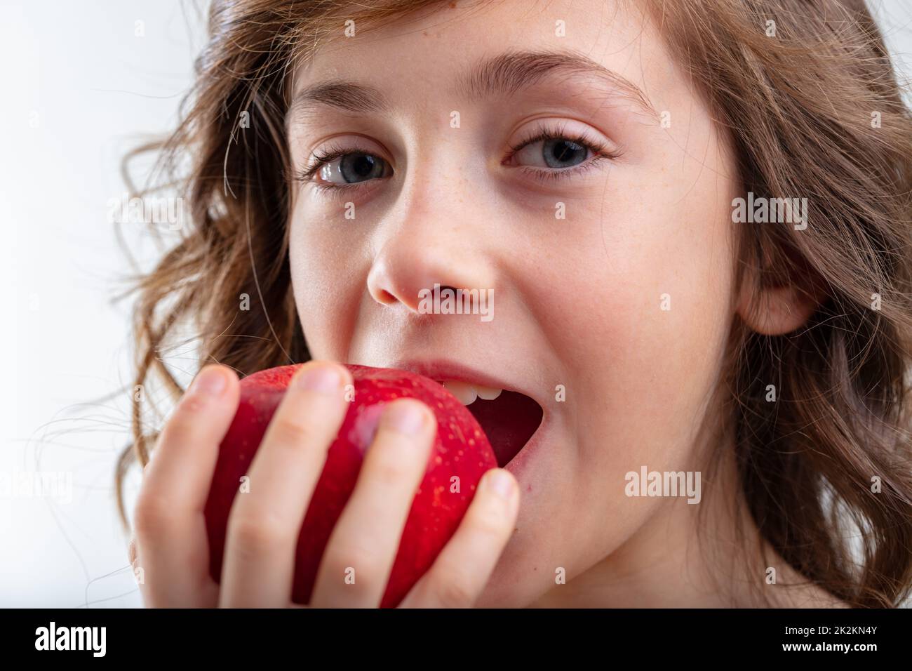 Young schoolgirl about to bite into a luscious red apple Stock Photo