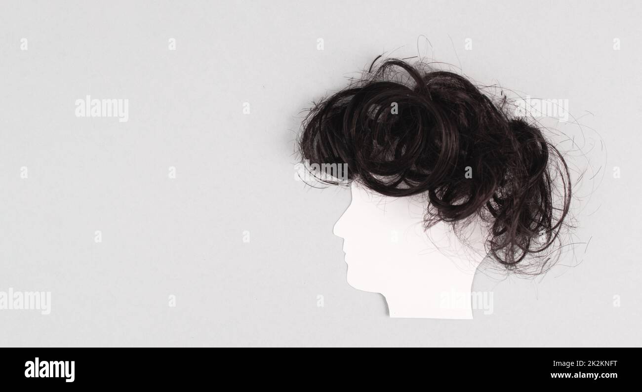 Silhouette of a face with a hairstyle, woman, man, transgender, copy space for text, portrait with dark hair, paper cut out Stock Photo