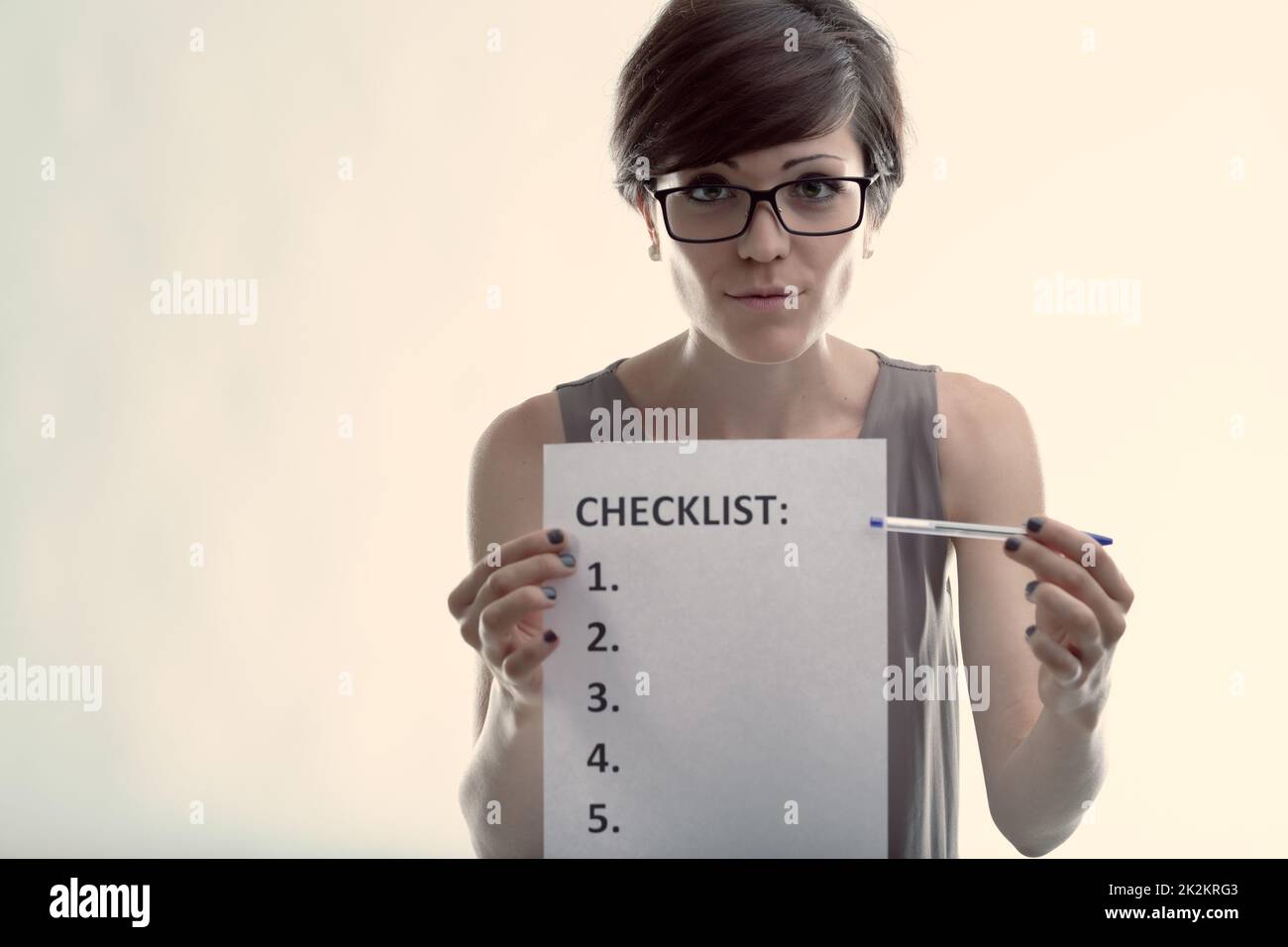 Earnest woman wearing glasses pointing to a blank checklist Stock Photo