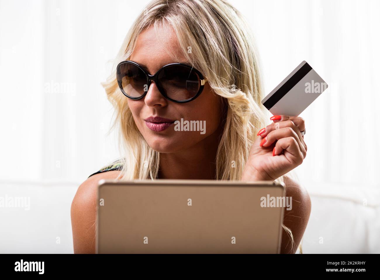 Grinning woman with credit card and tablet Stock Photo