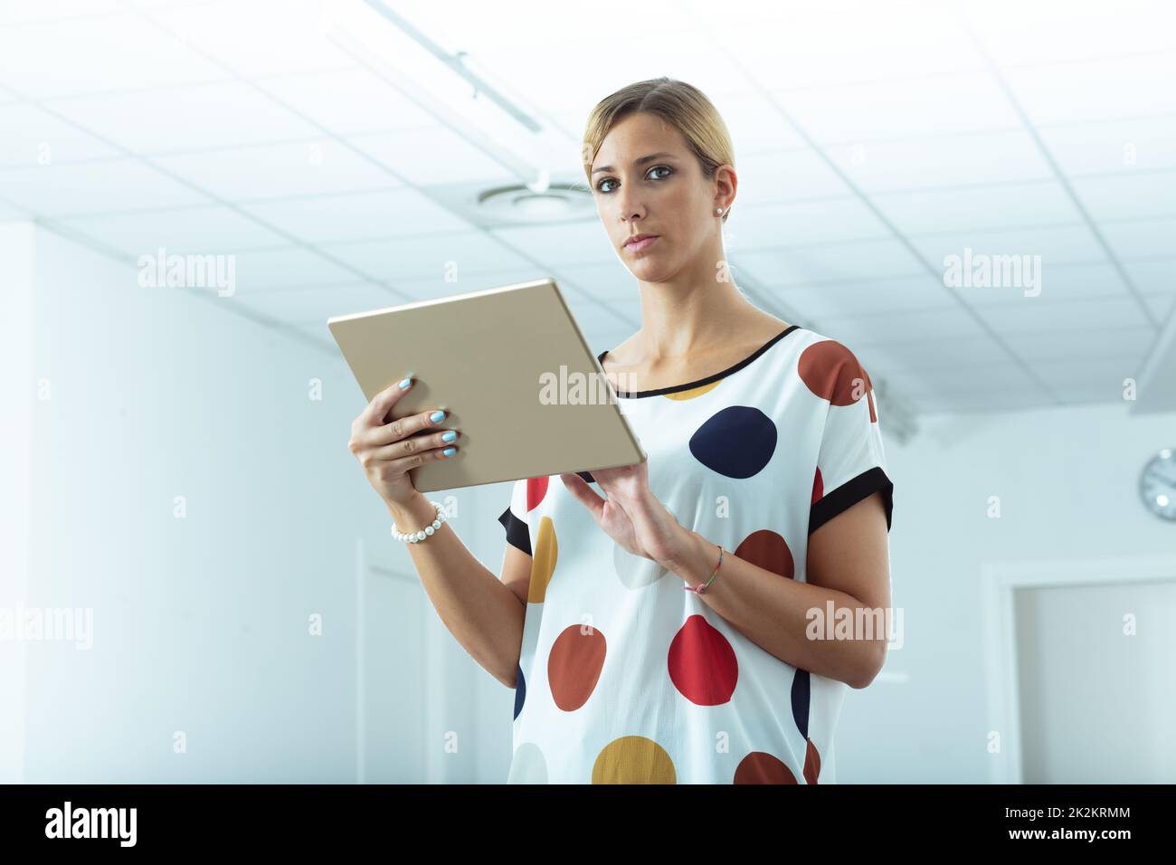 Woman holding a handheld tablet pc looking at camera Stock Photo