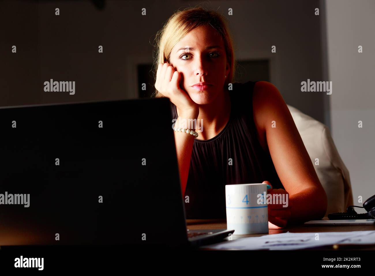 Glum elegant businesswoman working overtime at the office Stock Photo