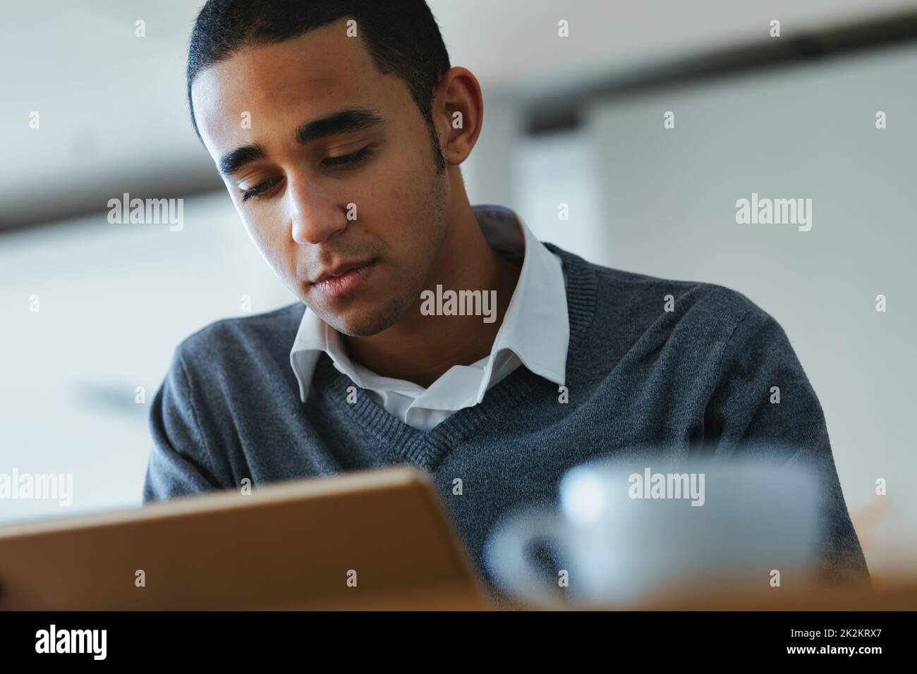 Serious young Black man engrossed in reading on a tablet pc Stock Photo