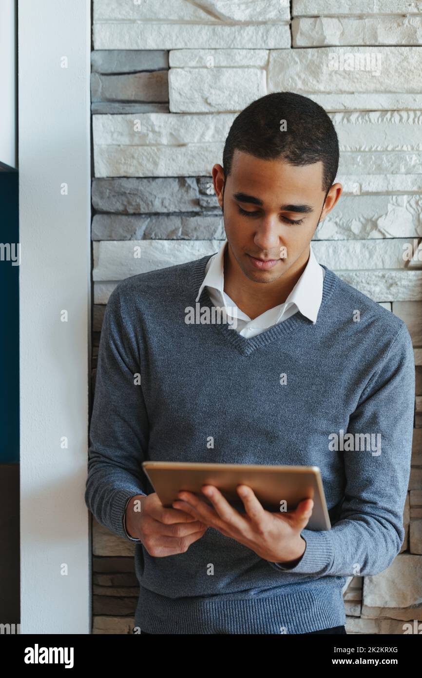 Young Black man standing reading on a tablet pc Stock Photo