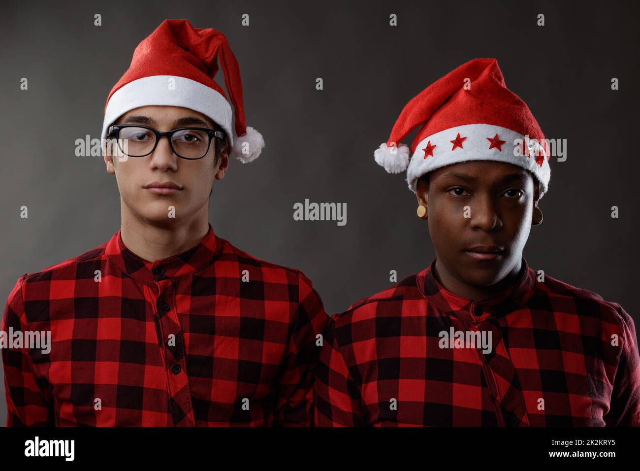 Two sombre young men wearing red Santa hats for Christmas Stock Photo