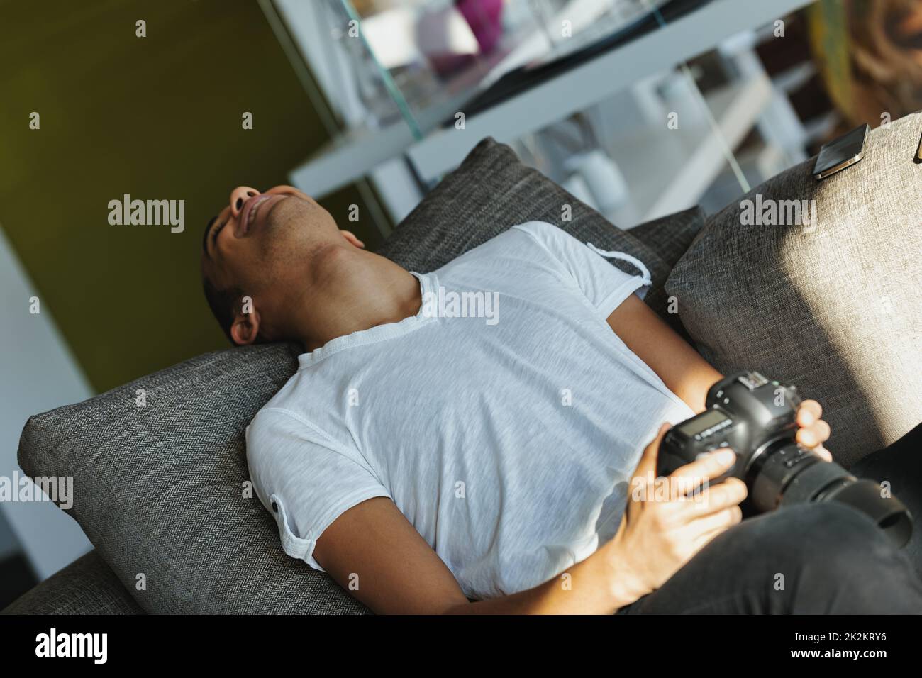 Young man and photographer laughing while holding his camera Stock Photo