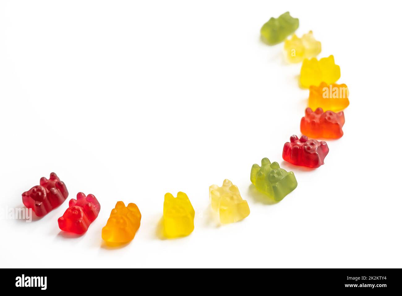 Multi-colored gummy bears lie in a semicircle on a light background with negative space, top view Stock Photo