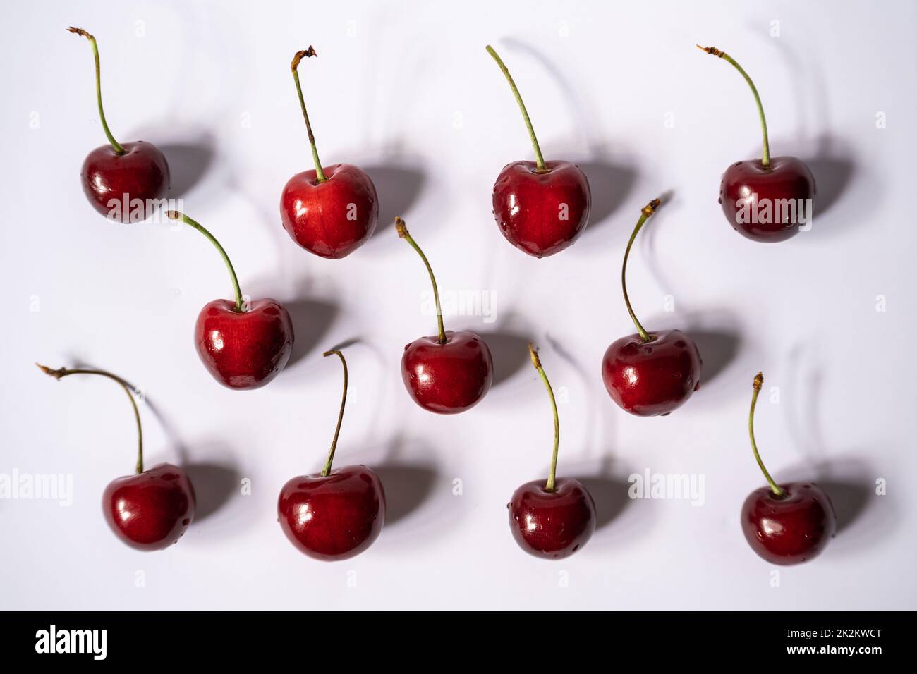 Cherries with a hard shadows side by side on a light background Stock Photo