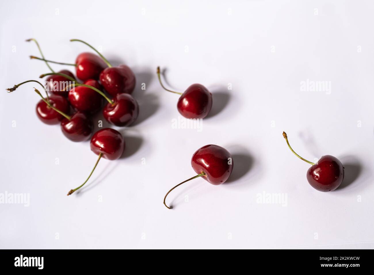 Three cherries lay separately from group of cherries Stock Photo