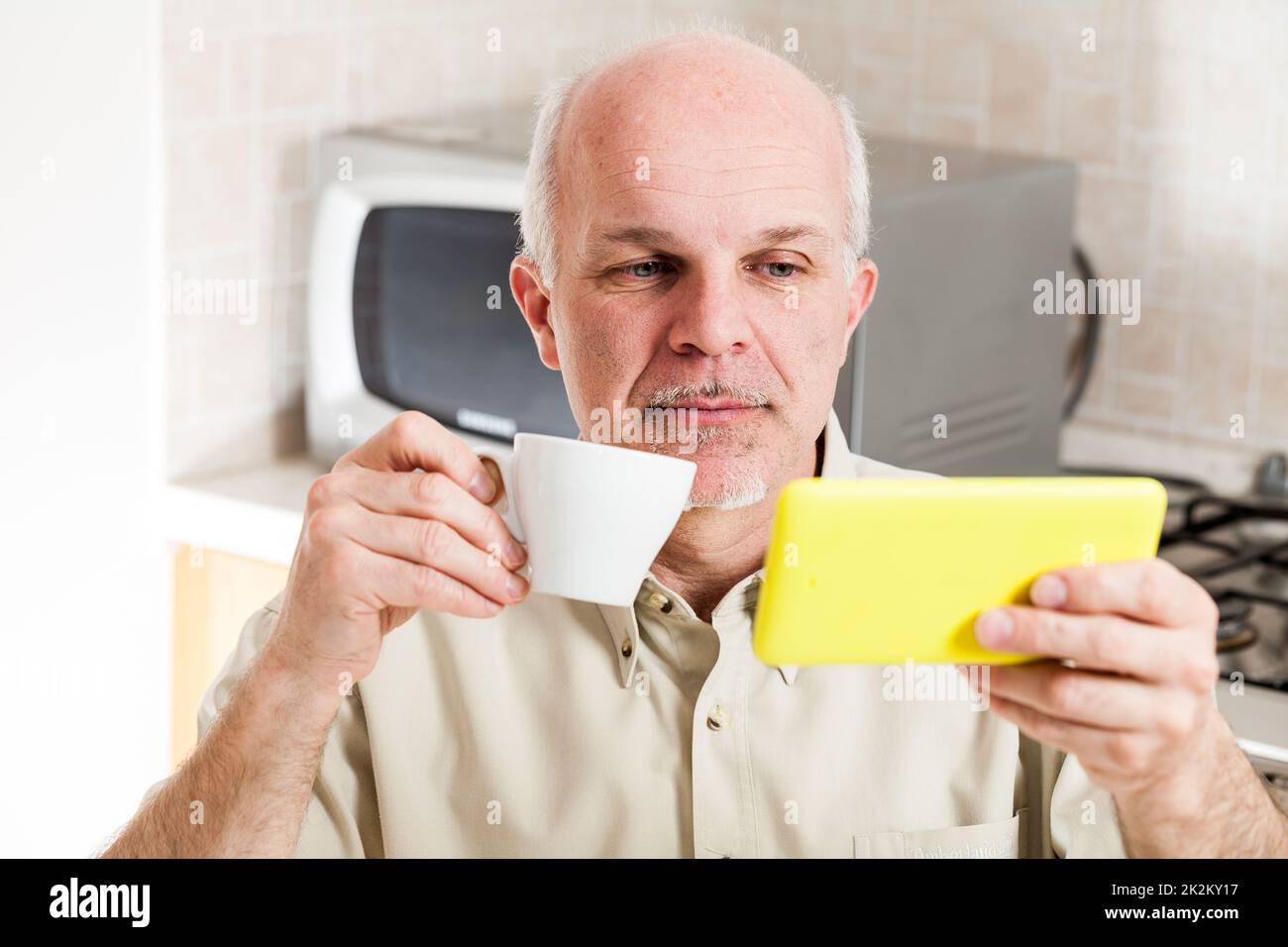 Handsome bearded mature man near microwave oven Stock Photo